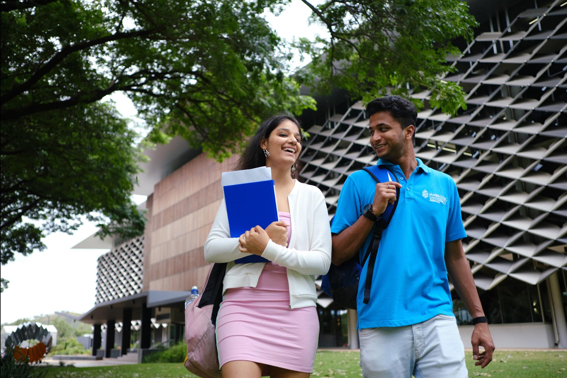 Male and female JCU students walking past The Science Place building at JCU Townsville, Queensland. 